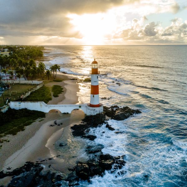 white and orange lighthouse beside sea
